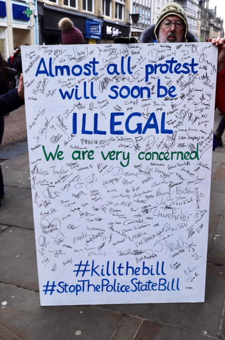 A man holds a petition poster board. It reads:
Almost all protest will soon be illegal. We are very concerned.
#killthebill
#StopThePoliceStateBill
