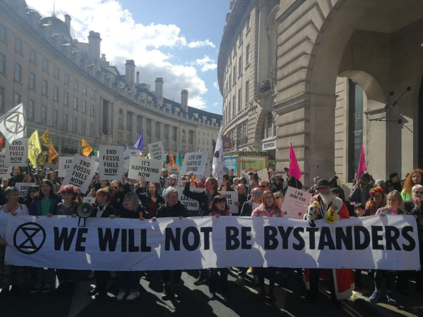 XR Rebels march down Regent Street with a banner: "We will not be bystanders"