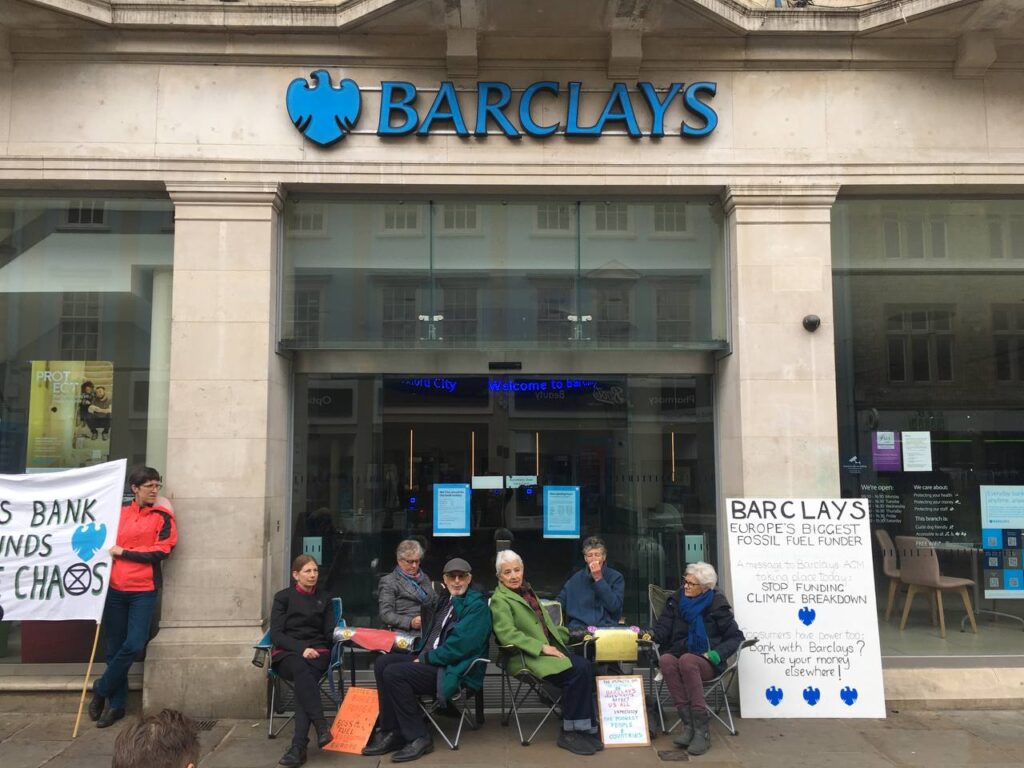 Six XR Oxford rebels lock on outside Barclays Bank in Cornmarket. A sign reads:
"Barclays: Europe's Biggest Fossil Fuel Funder. A message to Barclays AGM taking place today: Stop Funding Climate Breakdown. Consumers have power too: Bank with Barclays? Take your money elsewhere!"
Picture by Feng Ho