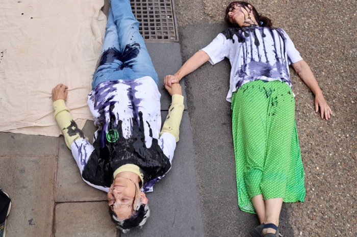 Two women covered in oil protesting Barclays Bank's investment in fossil fuels.