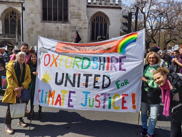 A group of people hold a colourful banner reading:
Greenpeace
Oxfordshire United for Climate Justice